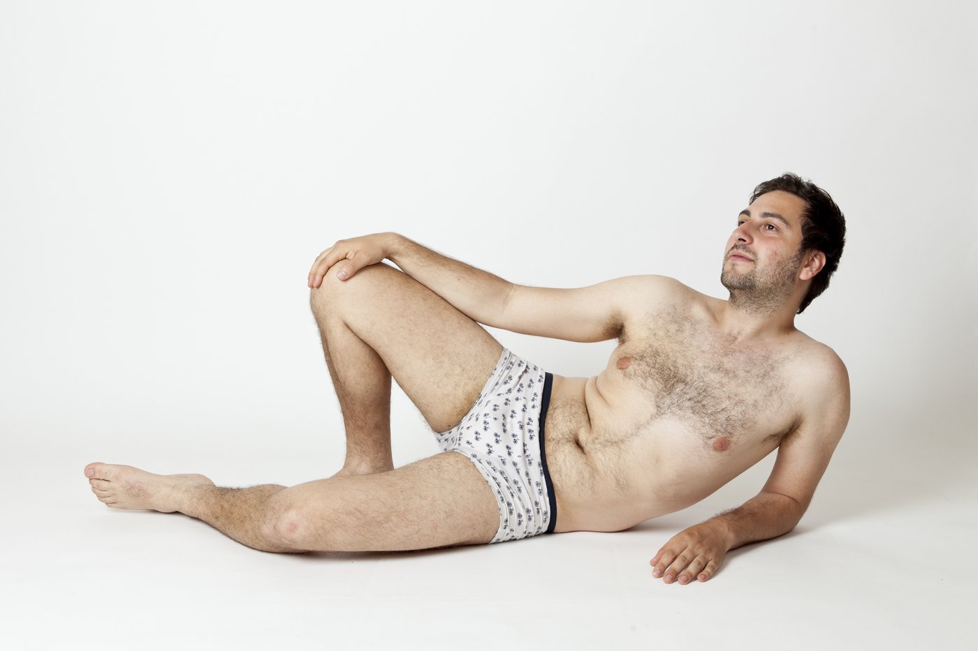 Berti Posierender Mann in Unterhose auf dem Boden sitzend