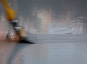 a brush paints on a grey colored wet surface